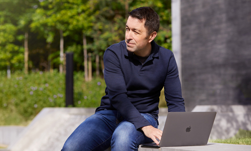 Rob assis dehors, travaillant sur son portable.