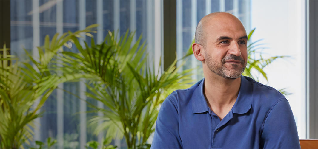 Ahmed assis à l’intérieur, souriant et regardant hors champ vers sa gauche.
