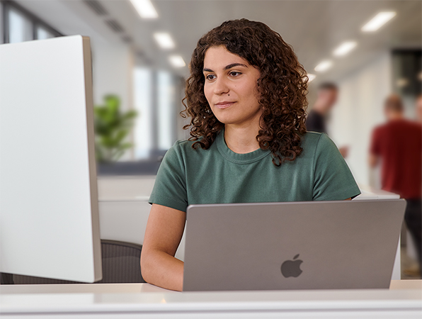 Membre de l’équipe Apple utilisant un MacBook et un Studio Display dans un bureau.