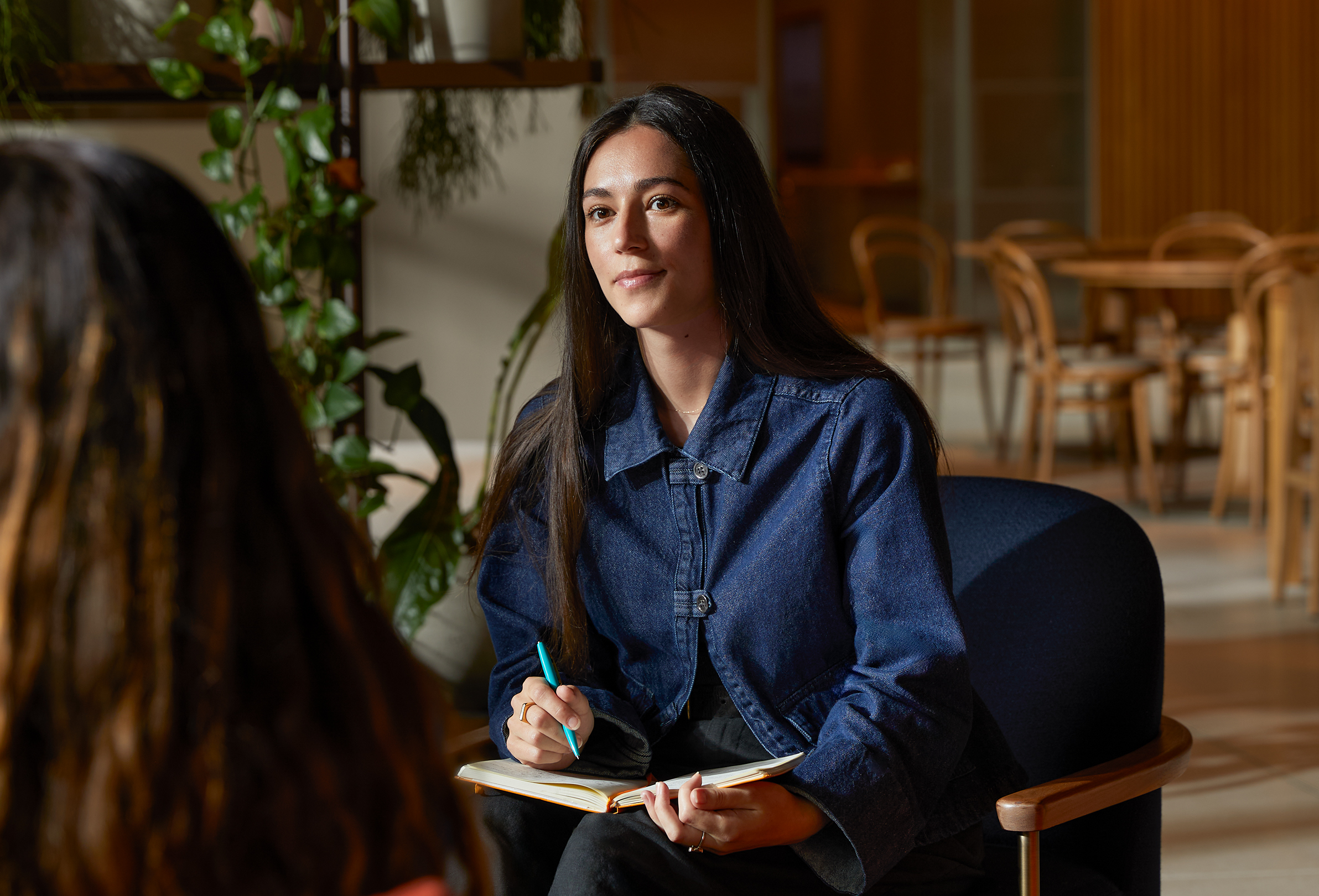 Membre de l’équipe Apple à une table dans une aire commune, discutant avec quelqu’un.