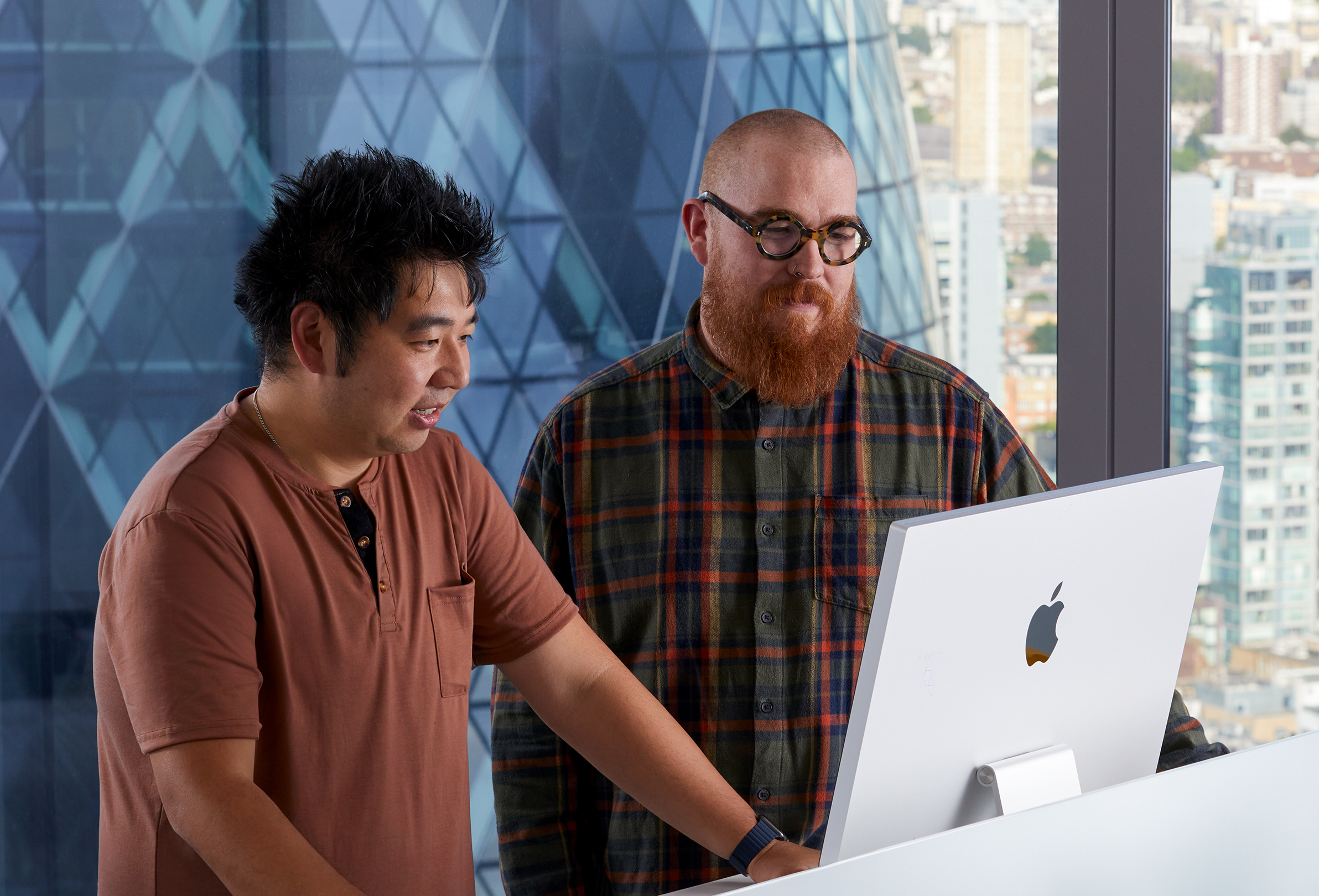 Deux membres de l’équipe Apple travaillant ensemble sur un iMac.