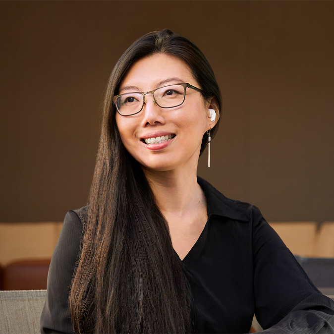Jessica 坐在室外微笑看向她的右側，背景是辦公區域。