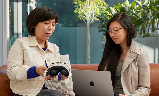 Jessica 在室內使用 MacBook，通往露臺的門開著，她和一位 Apple 同事坐在一起，對方正在向她展示 Apple Vision Pro。