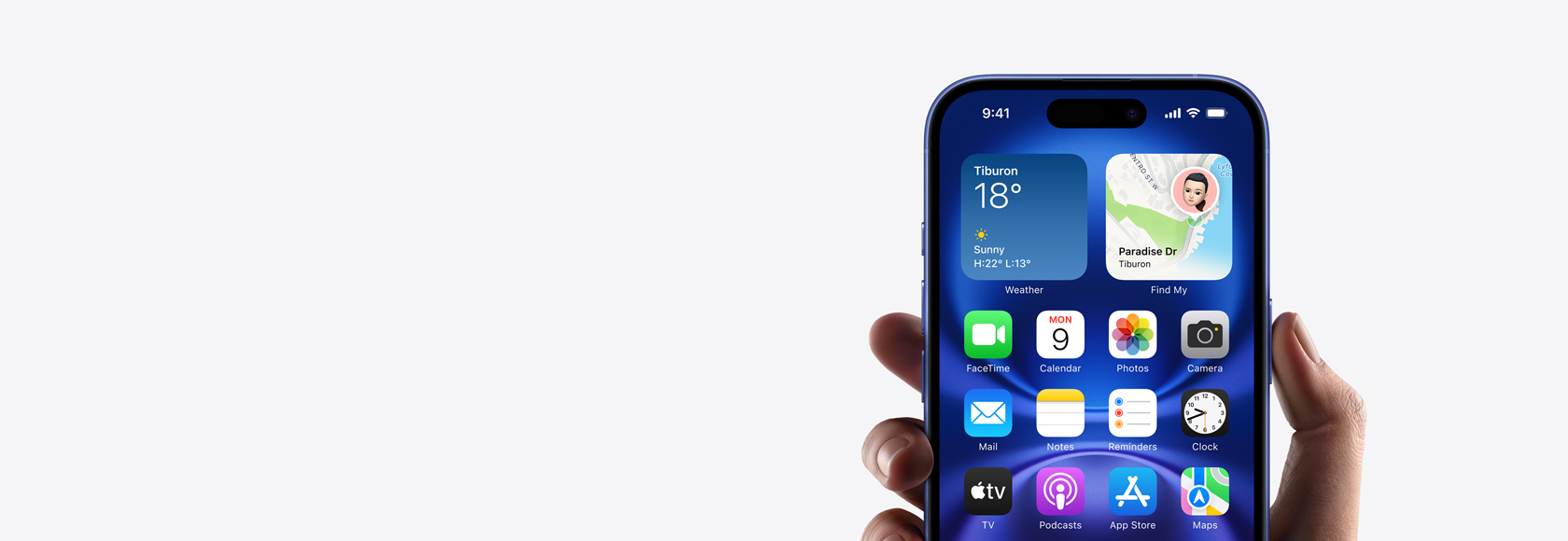 Hand holding iPhone 16 with screen showing Home screen photo, icons and widgets.