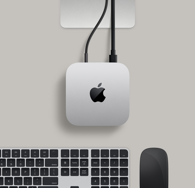 銀色 Mac mini 俯視圖,兩條連接線從背面插口連接至一部顯示器,旁邊放有黑色精妙滑鼠和黑色精妙鍵盤。