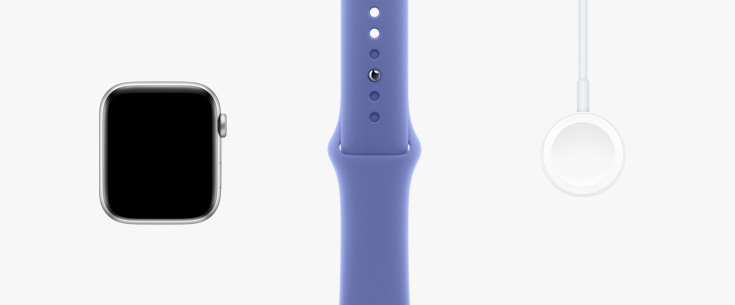 Stilt opp på rekke: maskinvaren i Apple Watch vist forfra, Sport Band i stjerneskinn og en magnetisk lader-til-USB‑C-kabel.