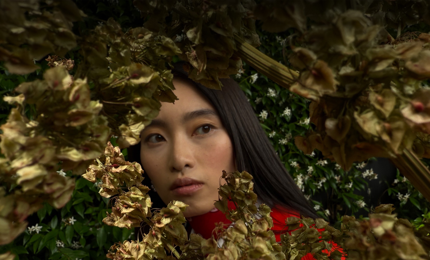 Close-up photograph of a woman surrounded by foliage