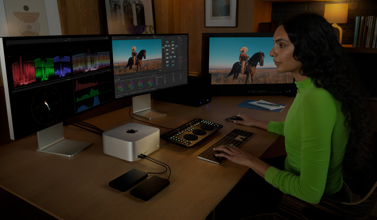 Um profissional a editar ficheiros num Mac Studio ligado a três monitores