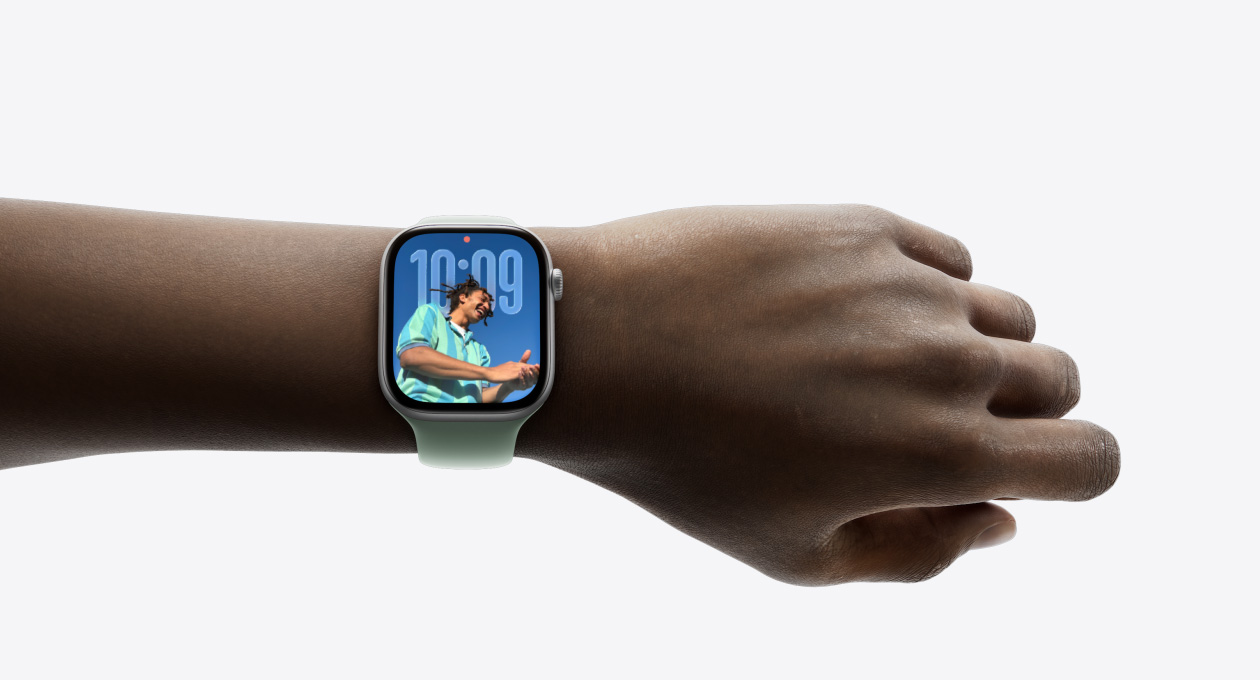 손목에 착용된 실버 Apple Watch와 고무 밴드의 클로즈업 이미지, 새로운 Liquid Glass 디자인을 보여주는 모습
