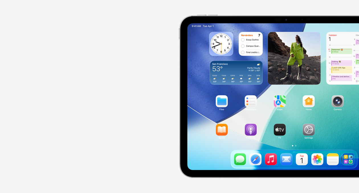iPad nằm ngang, chỉ thấy phía bên trái màn hình, Màn Hình Chính với các tiện ích xếp chồng lên nhau bao gồm đồng hồ trong mờ thể hiện hiệu ứng Liquid Glass, ứng dụng Tìm, tiện ích Thời Tiết, hai hàng ứng dụng nhỏ hơn và dock